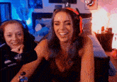 two women are laughing in front of a shure microphone .