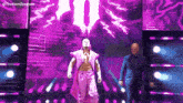a man in a purple robe is walking on a stage with a man in a suit .