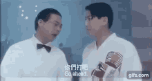 two men are standing next to each other in a room and talking .