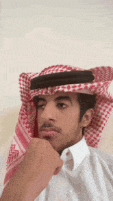 a man wearing a white shirt and a red and white checkered head scarf