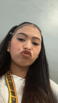 a woman wearing a white shirt and a yellow lanyard that says off white on it makes a face