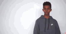 a young man wearing a grey nike hoodie stands in front of a white background