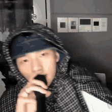 a man wearing a hooded jacket is singing into a microphone .