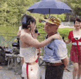 a woman is hugging a man while holding an umbrella in a park .