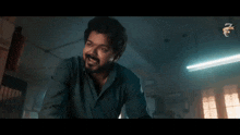 a man with a beard is standing in a dark room with a light on the ceiling .