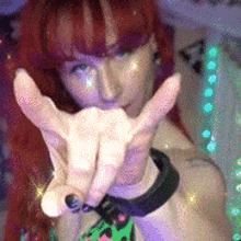 a woman with red hair is making a hand gesture with her fingers