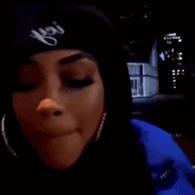 a woman is applying lip gloss to her lips while wearing a black hat .