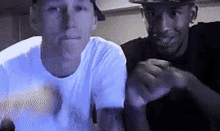 two men are sitting next to each other and one is wearing a hat