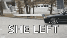a black car is driving down a street and the words she left are on the side of it