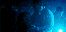 a man and a woman are hugging in a dark room with blue lights behind them