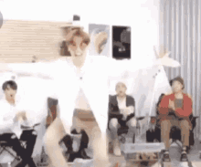 a group of people are sitting in chairs in a room while a man is dancing in front of them .