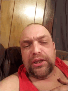 a man with a beard wearing a red tank top