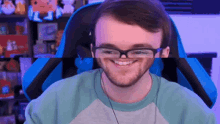 a man wearing glasses is smiling while sitting in a gaming chair