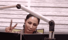 a woman is giving a peace sign in front of a computer monitor .