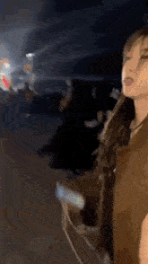 a woman in a brown jacket is standing in a crowd of people .