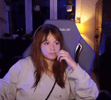a woman wearing headphones is sitting in a versus gaming chair