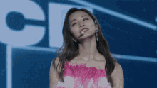 a woman in a pink dress is standing in front of a large letter c