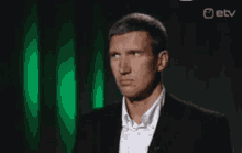 a man in a suit stands in front of a green screen that says " etv " on it