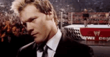 a man in a suit is standing in front of a wrestling ring .