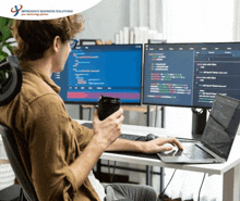 a man sits at a desk with two computer monitors and a laptop with the words impressico business solutions on the bottom left