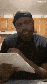 a man is sitting at a table with a notebook and a pen in his hand .
