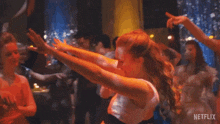 a woman is dancing on a dance floor with her arms in the air in a club .