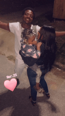 a man and woman holding a baby with the date mar 22 on the bottom right