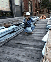 a man wearing a hard hat is squatting on a wooden floor
