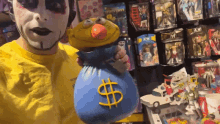 a man in a yellow shirt is holding a blue money bag with a dollar sign on it