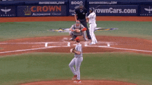 a baseball game is being played in front of a crown automotive group banner