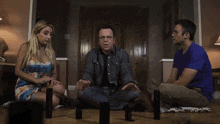 two men and a woman are sitting on the floor with their feet crossed