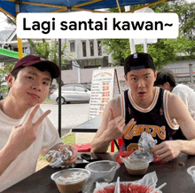 two boys sitting at a table with a sign that says lagi santai kawan