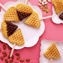 a white plate with a heart shaped waffle on a stick on a pink table