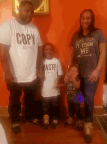 a man wearing a copy t-shirt stands next to a woman and child