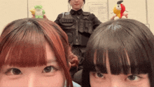 two girls are posing for a picture with a man holding a stuffed animal in front of a wall that says information