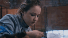 a woman in a chef 's uniform is sitting at a table with a plate of food in front of her .