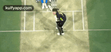 a man is playing a game of cricket on a field with a sign that says kulfyapp.com