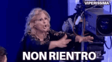 a woman is standing in front of a camera with the words non rientro written above her .
