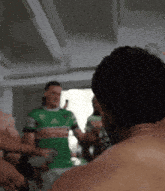 a man in a green adidas shirt stands in a room