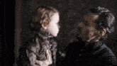 a man and a little girl are looking at each other in a dark room