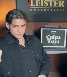 a man stands in front of a sign that says culpa tuya