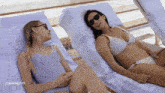 two women in bikinis are laying on lounge chairs with the number 1164942770