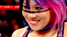 a woman with purple and blue hair is smiling and wearing a mask .