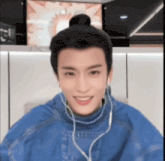a young man wearing headphones and a blue jacket is smiling