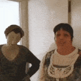 two women are standing next to each other in a hallway . one of the women is wearing a mask .
