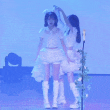 three girls in white dresses and boots are standing on a stage