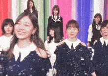 a group of young women are standing in front of a colorful curtain .
