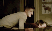 two men are laying on top of each other on a table in a dark room .