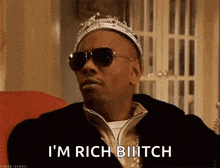 a man wearing a crown and sunglasses says " i 'm rich biiitch "