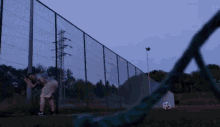 a man leans against a fence looking at a soccer ball